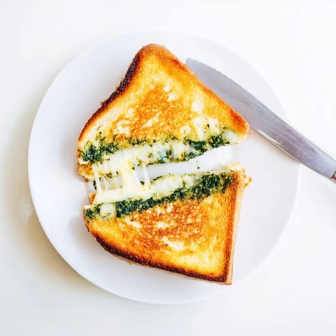 Golden-brown sourdough grilled cheese slices filled with vibrant green spinach pesto and melted mozzarella and cheddar.