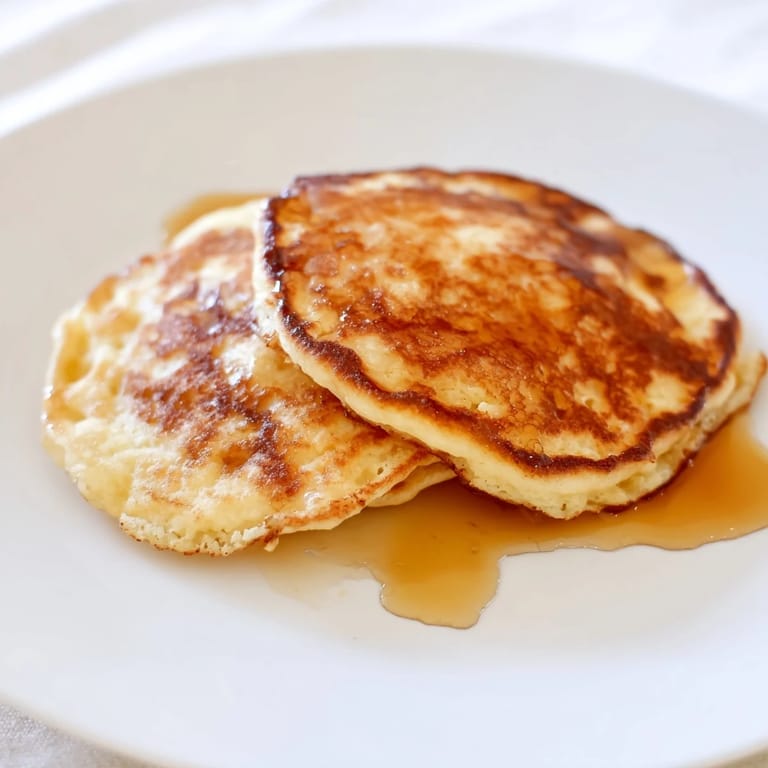 A stack of tender cottage cheese pancakes, drizzled with honey and served for a delightful breakfast.