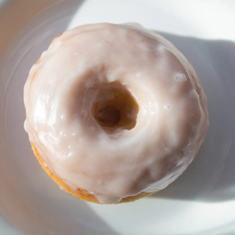 These classic American muffin tin donuts have a glistening glaze, perfect for a cozy dessert.