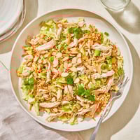 A close-up of Crunchy Ramen Chicken Salad with shredded cabbage, carrots, and toasted almonds tossed in a glossy sesame dressing.