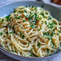 Creamy lemon butter pasta with silky Parmesan sauce and fresh parsley garnish, served in a white bowl.