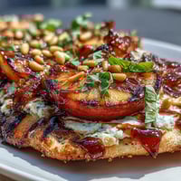 Grilled flatbread with BBQ sauce, melted Brie, and juicy peaches, topped with fresh basil.  